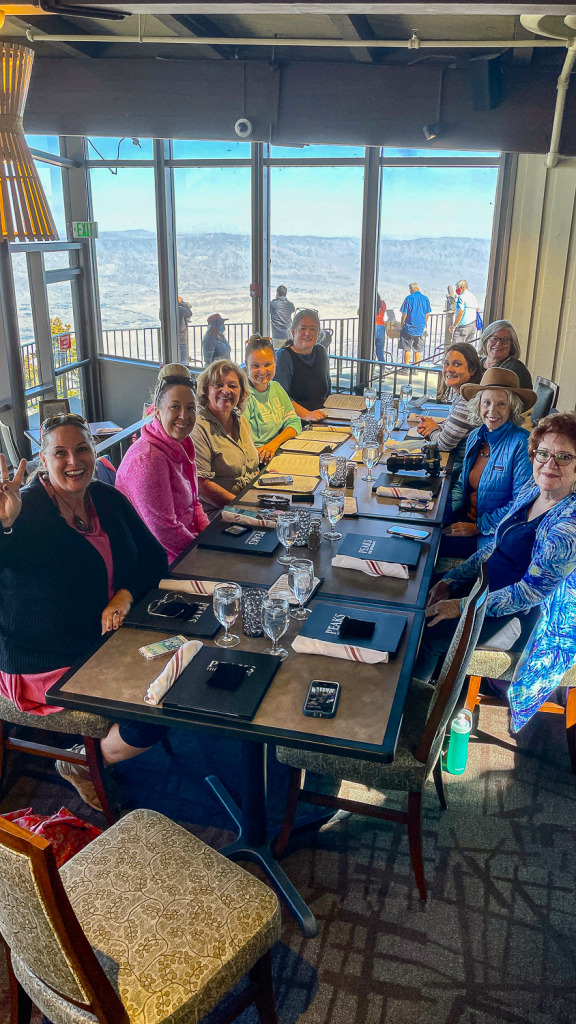 a group of women sitting at table at Peaks Restaurant with Palm Springs in the valley below
