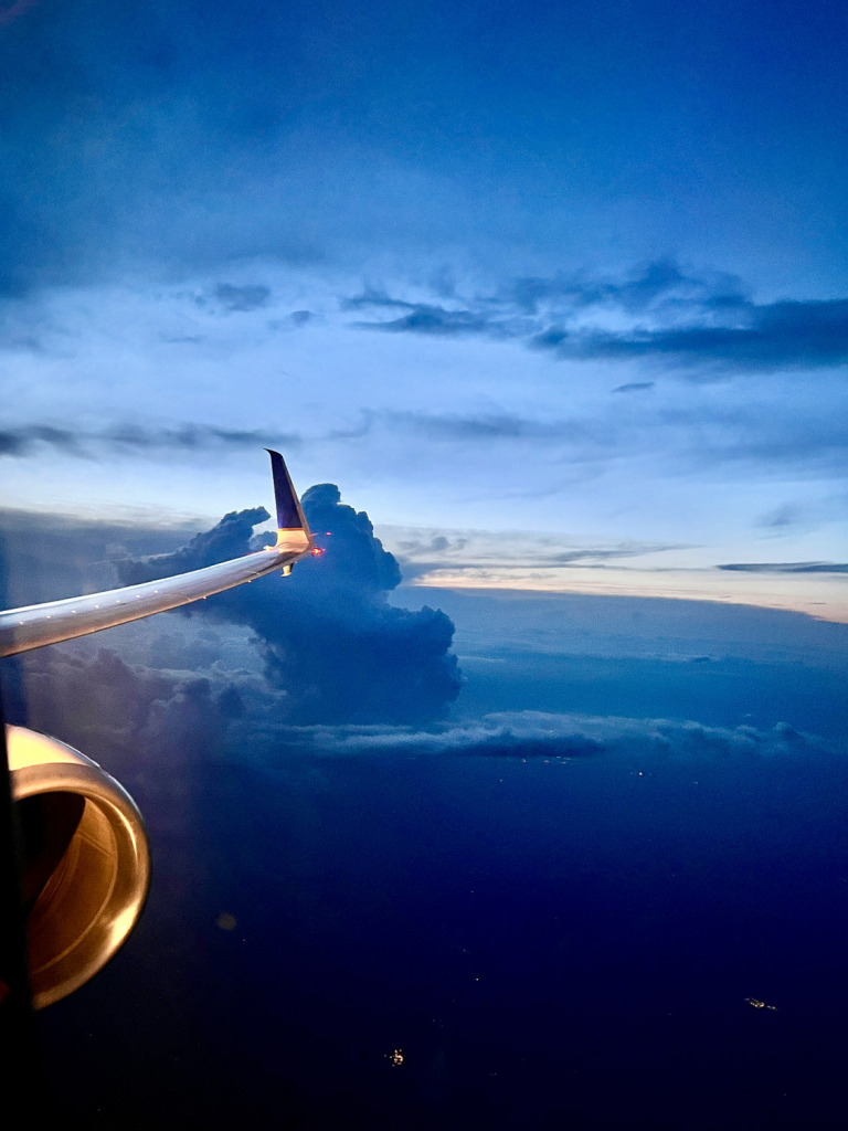 Evening photo of airplane wing and engine with storm clouds in the distance, near Richmond, VA.