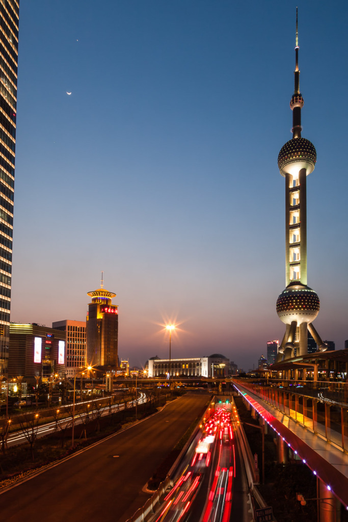 Traffic rushes toward a tunnel under the Huangpu River in Shanhai at dusk. The Oriental Pearl Tower is to the right.