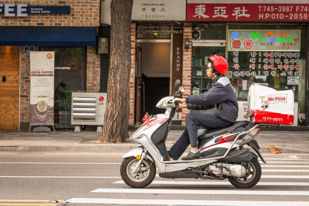 Photo of delivery motorcycle speeding by and frozen with a fast shutter speed in Seoul, South Korea.