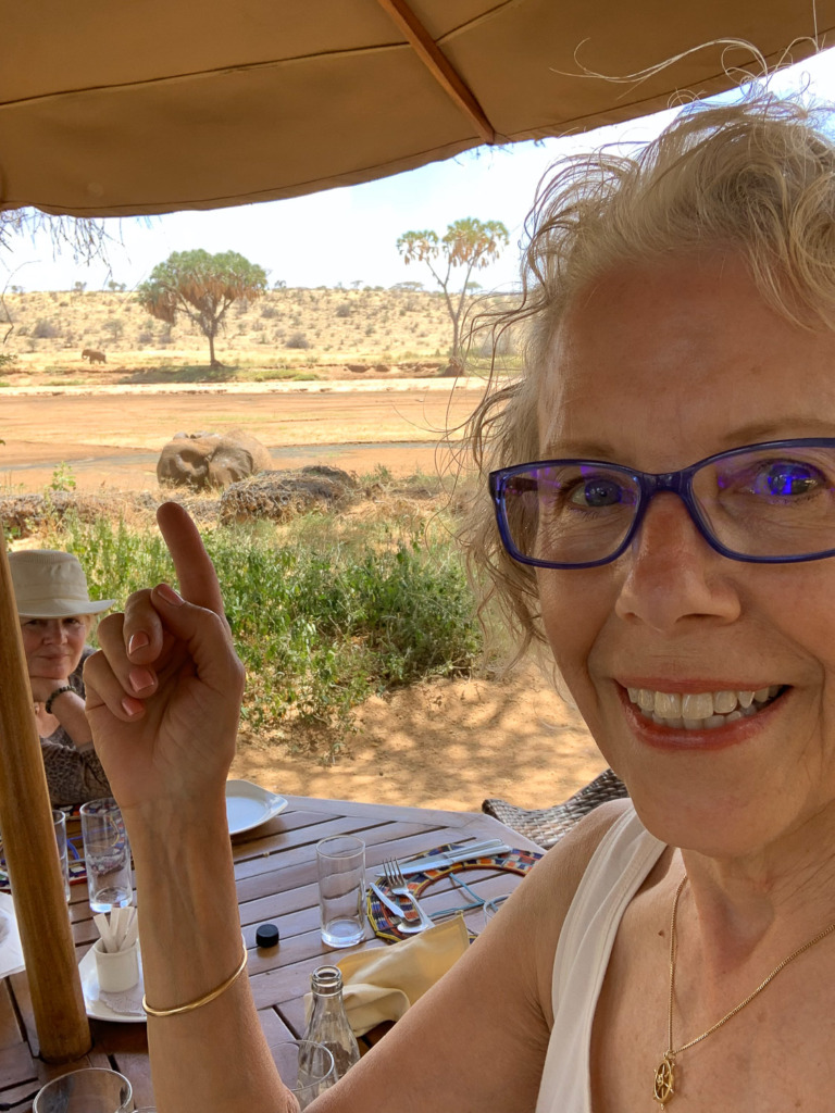 when you take a selfie the camera will be mirrored as you pose. This woman is pointing to an elephant behind her.