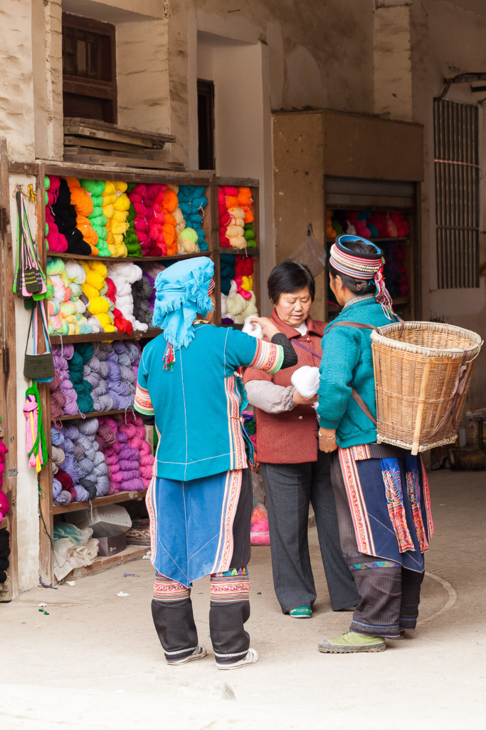 Two women are buying yarn at the market in Xinjie, China.