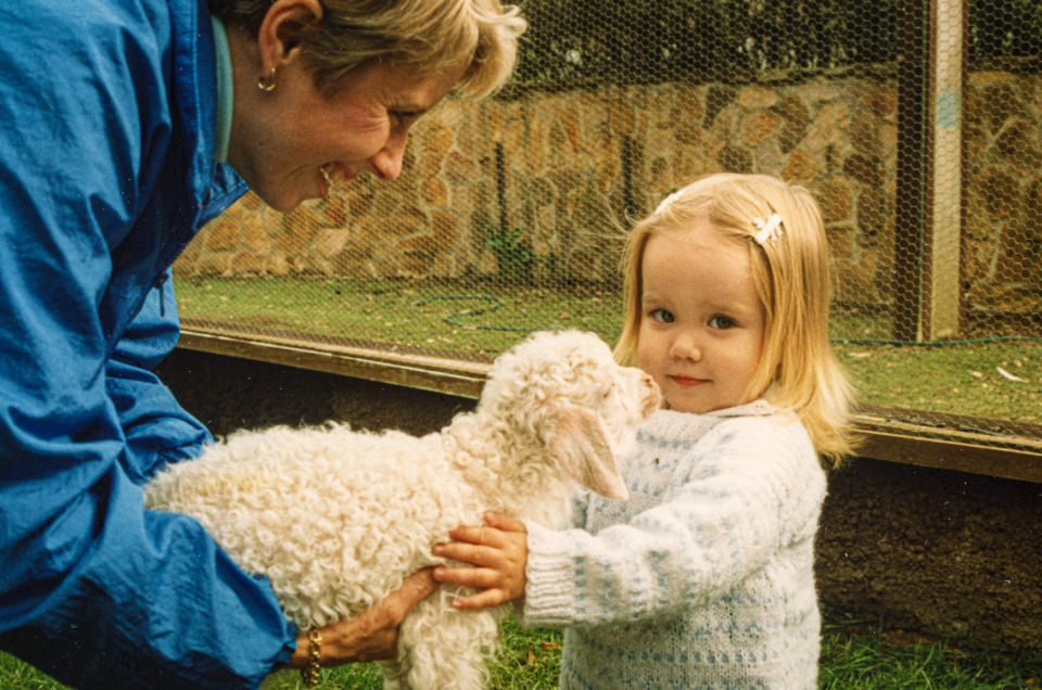 A woman and her daughter meet a 2-week-old goat.