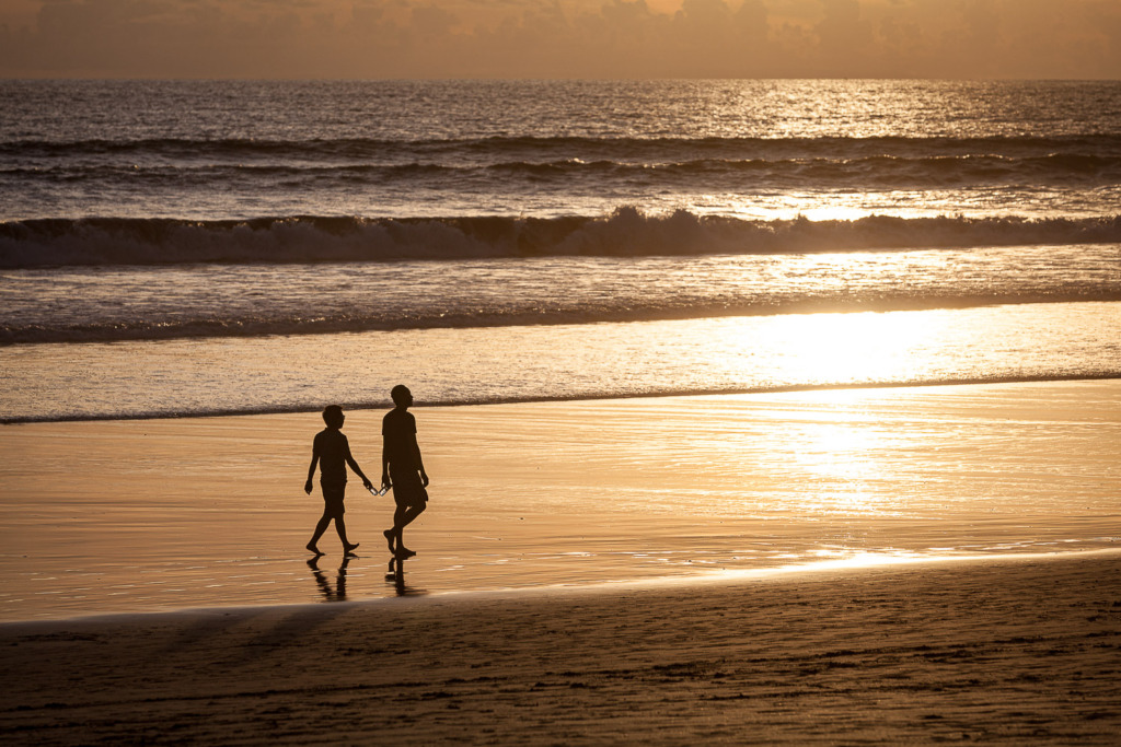 beach photo of two men walking on beach at sunset in Bali
