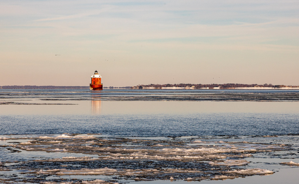 Sandy Point Shoal Lighthouse in winter, with ice floating on the water.
